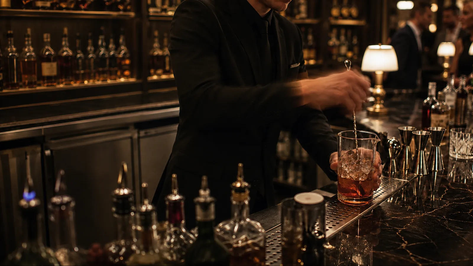 Bartender stirring a cocktail at a dimly lit marble bar