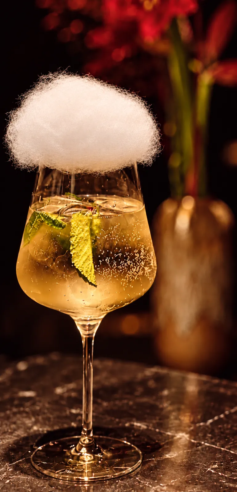 Signature cocktail crowned with a cotton-candy cloud, red amaryllis in the background